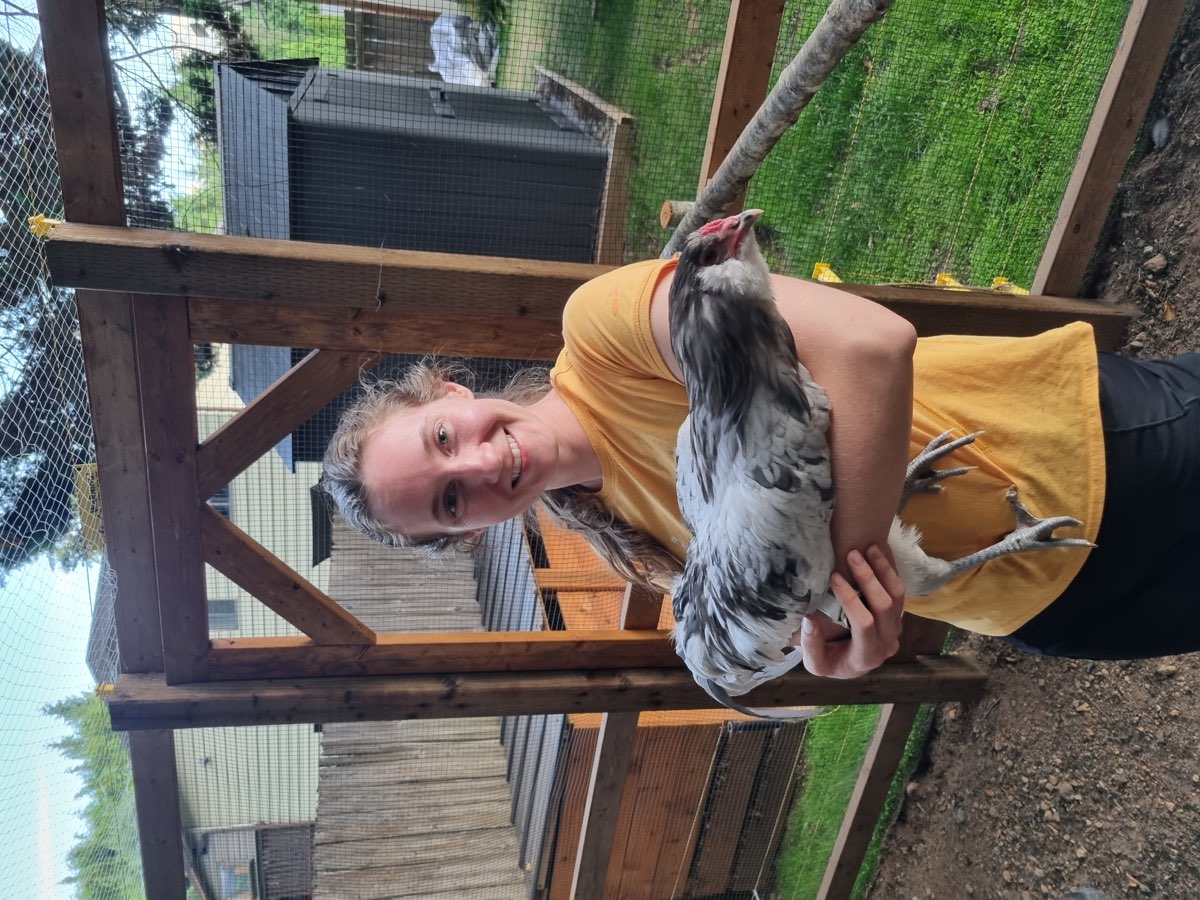 Madi holding a hen in the coop run at home